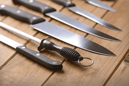 Several Sharp Chef Knives Laid Out On Wood